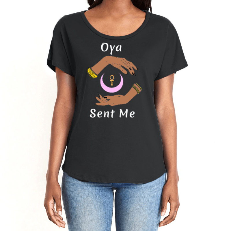 Feel the magic of wearing this black comfortable women's T-shirt with the name of the West African goddess Oya, and the message - "Oya Sent Me" in white letters. It has brilliant graphics of hands circling a new moon with an ankh. It is fabric laundered for relaxed fit.